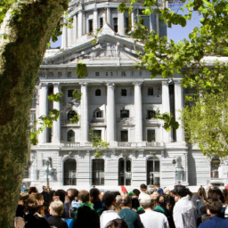 An image of a large building surrounded by trees and a crowd of people in the foreground.