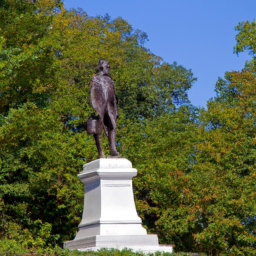 A historical statue of a famous individual surrounded by trees in a park setting.
