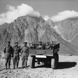 description: a group of soldiers in camouflage uniforms standing in front of a military vehicle, with a mountain range visible in the background.