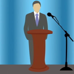 A person in a suit standing in front of a podium with a microphone.