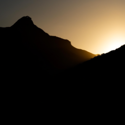 A silhouette of a mountain range, with the sun setting behind it.