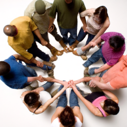 A group of people standing in a circle, all facing each other, with their hands clasped together in a gesture of unity.