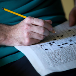 description: an anonymous person holding a pencil and solving a crossword puzzle.