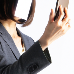a woman in a business suit looking at a smartphone, her face partially obscured by the phone's screen.