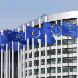 description: an image of a group of european union flags flying in front of a building, symbolizing the unity and resilience of the eu in the face of the ukraine war.description: an anonymous image of a group of european union flags flying in front of a building, symbolizing the unity and resilience of the eu in the face of the ukraine war. the flags are waving in the wind, creating a dynamic and powerful visual representation of the eu's response to the conflict. the building in the background is grand and imposing, suggesting the strength and determination of the eu in the face of adversity.
